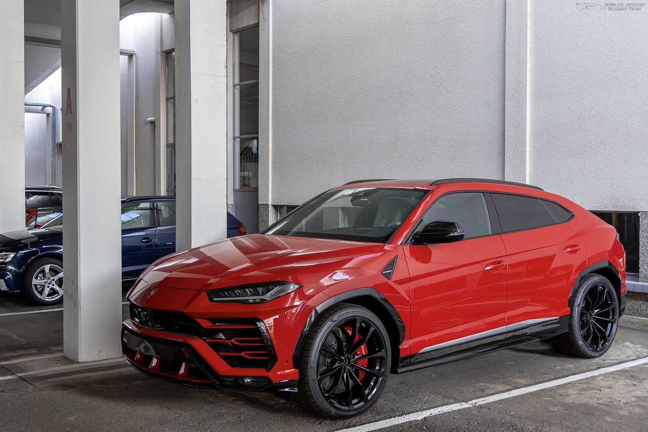 Lamborghini Urus vermelho estacionado num estacionamento entre colunas brancas